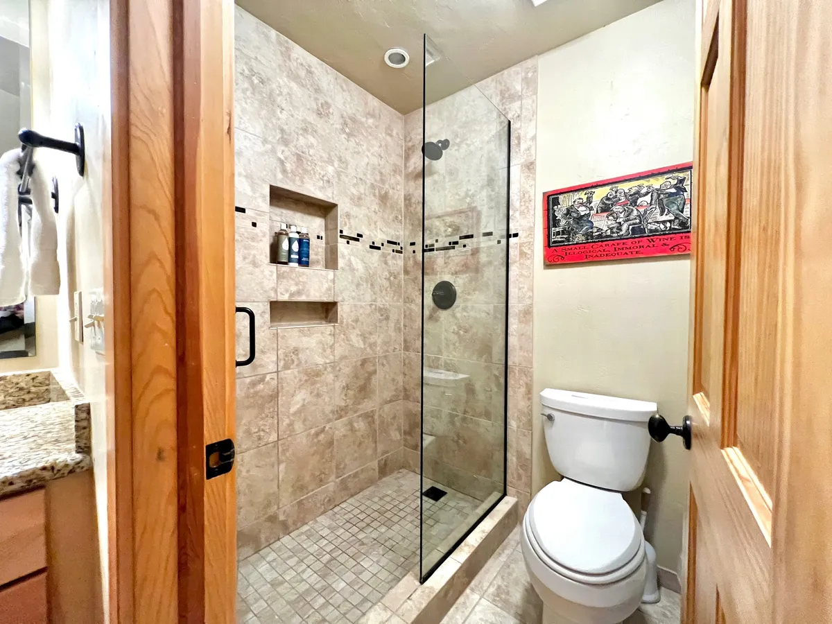 A modern bathroom interior featuring a glass shower enclosure, sleek granite countertop, and decorative wall art. The space is bright and inviting, with clean lines and contemporary finishes that create a refreshing atmosphere ideal for both getting ready and unwinding.